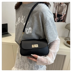 Detail of elegant black leather crossbody bag featuring a golden textured metal buckle