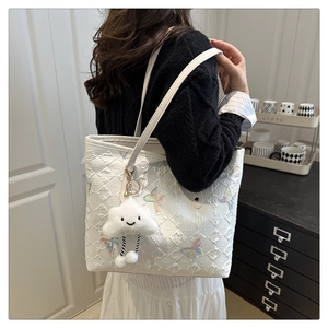 Detail of white quilted tote bag with butterfly embroidery and plush cloud keychain