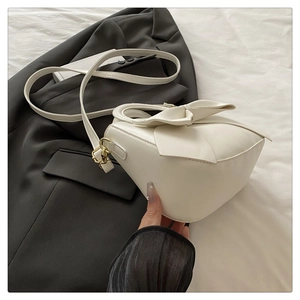 Detail of white bow-knot leather handbag with golden hardware and adjustable shoulder strap