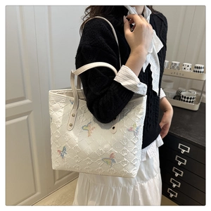 Detail of white tote bag featuring colorful butterfly embroidery and embossed texture
