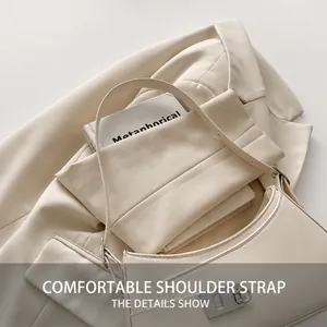 Détail du sac selle en cuir crème avec une large bandoulière et une boucle en métal argenté