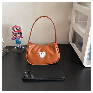 Detail view of brown vintage mini shoulder bag with white heart and phone for scale