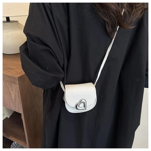 Detail view of a white litchi pattern leather mini bag with a silver heart-shaped clasp