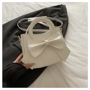 Detailed shot of white bow handbag with glossy texture and elegant gold hardware accents