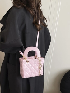 Rosafarbene Stepptasche mit goldener Kette an einem Modell im dunklen Mantel