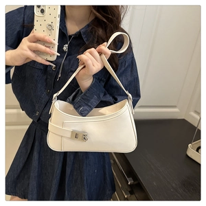 Gros plan du sac demi-lune beige avec boucle argentée porté par un mannequin en robe