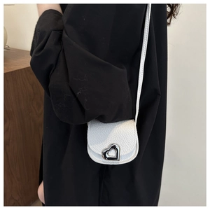 Detail of white mini crossbody bag with silver heart lock and lychee leather texture