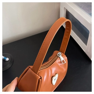 Detail view of brown PU leather shoulder bag with sparkling rhinestone heart decoration