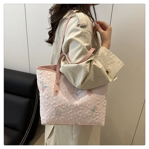 Close-up of butterfly embroidery and letter embossing on pink leather tote bag
