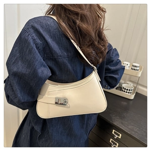 Détail d'un sac sous le bras en cuir blanc cassé avec boucle argentée sur denim
