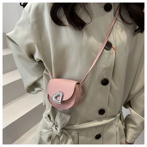 Detail of pink pebbled leather mini saddle bag with silver heart buckle on model