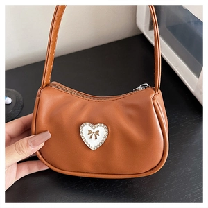 Close-up of brown PU leather handbag featuring a decorative heart patch with golden bow detail