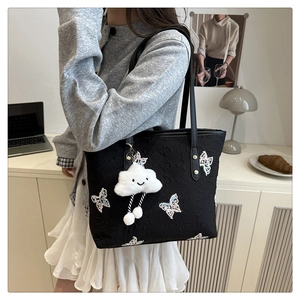 Détail du cabas en jacquard noir avec broderie papillon et breloque nuage en peluche