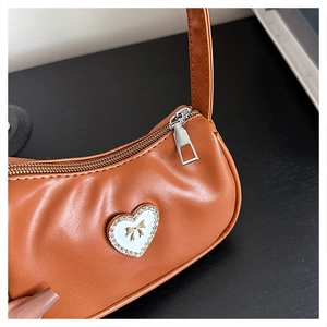 Close-up of brown faux leather baguette bag featuring a rhinestone heart with golden bow