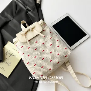 Detail of cream backpack with red bow prints and pearl charm on the flap cover
