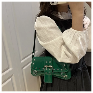 Close-up of green patent leather baguette bag featuring punk silver rivets and metal buckle