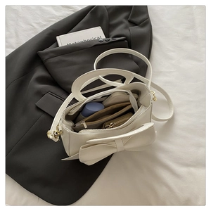 Detailed top view of a cream white bow handbag showing spacious multi-compartment interior