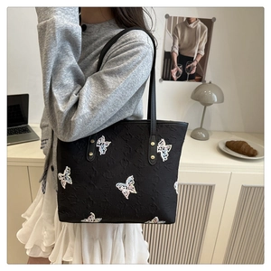 Detail of colorful butterfly embroidery and jacquard texture on black tote bag