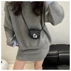 Detail of mini black lychee leather crossbody bag with silver heart-shaped metal buckle