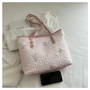 Macro view of pink tote bag showing intricate butterfly embroidery and leather texture
