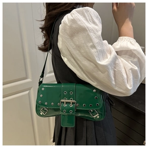 Close-up of green patent leather underarm bag with silver studs and metal buckle detail