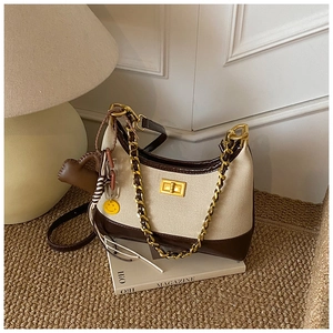 Detail of canvas crossbody bag with gold chain strap on a lifestyle magazine background