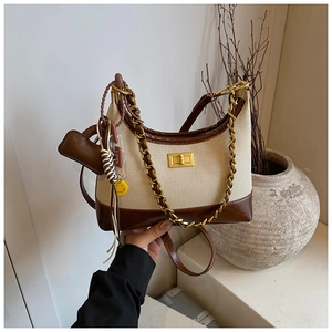 Detail of canvas and leather crossbody bag with gold chain and yellow smiley charm