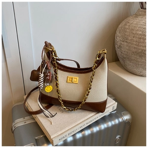 Close-up of canvas and leather crossbody bag with golden twist lock and charm