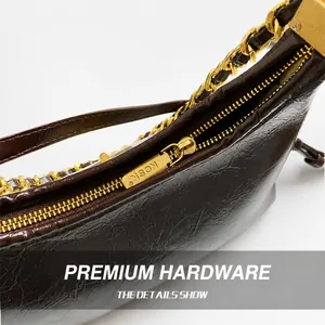 Macro shot of dark brown polished oil wax leather bag with premium gold hardware