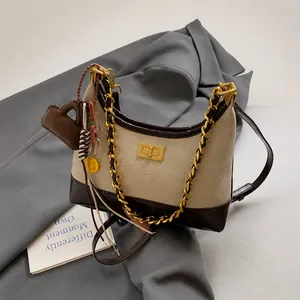 Detail of canvas crossbody bag with leather trim, metal twist lock and charms