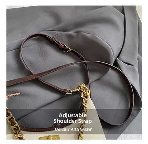 Detail of adjustable leather shoulder strap with gold-tone hardware and chain on canvas bag