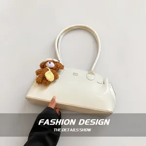Detail van gebroken witte schoudertas van kunstleer met schattige teddybeer hanger