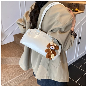 Detail van de witte laklederen schoudertas met een schattige bruine teddybeer-bedeltje