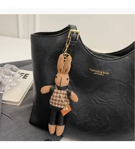 Gros plan du pendentif lapin en tricot avec gilet pied-de-poule sur sac en cuir noir