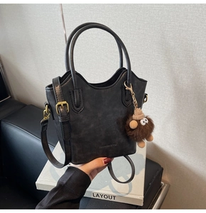 Dettaglio ravvicinato della borsa a secchiello retrò nera con inserti dorati e charm