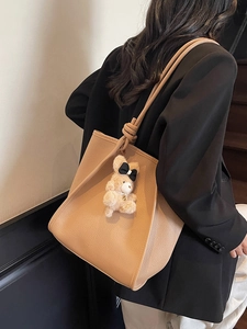 Brown large capacity leather tote bag with knotted shoulder strap and plush bear charm