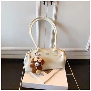 Detail van crèmekleurige kunstlederen schoudertas met teddybeer hanger en logo