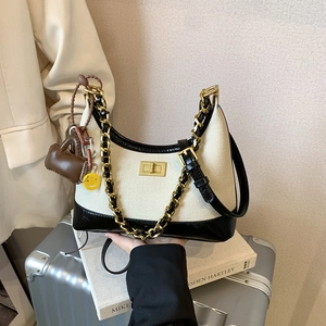 Chic beige canvas and black patent leather crossbody bag with gold chain and charms
