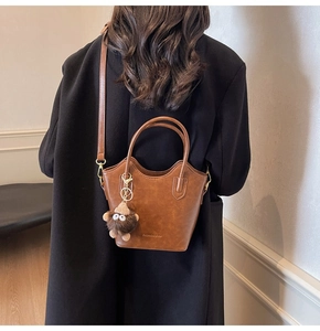 Borsa a secchiello retrò marrone con ciondolo a mostro indossata con cappotto nero