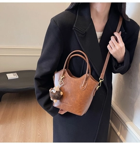 Borsa a secchiello retrò marrone con ciondolo in peluche e tracolla indossata da modella