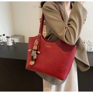 Détail du cabas en cuir synthétique rouge avec logo doré et pendentif lapin chic