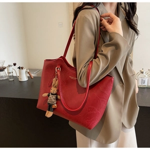 Détail du sac cabas en cuir rouge avec pendentif lapin et imprimé porté par un mannequin