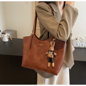 Détail du sac cabas vintage marron avec texte tendance et charm de lapin suspendu