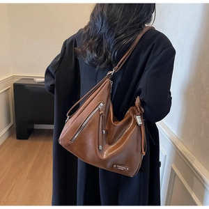 Détail d'un sac cabas en cuir marron vintage avec fermetures éclair et pompons élégants