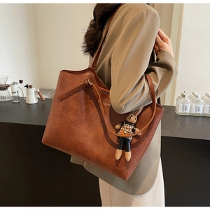 Détail du sac cabas vintage en cuir marron avec texte blanc et breloque lapin à carreaux