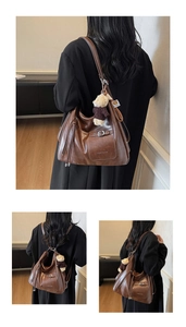Detail of a brown leather hobo bag with ZSKE PARIS logo and plush bear pendant
