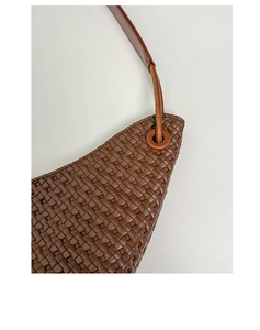 Macro detail of brown woven leather texture and circular metal eyelet on a tote bag