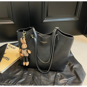 Détail d'un grand sac cabas rétro en cuir noir avec un charmant pendentif lapin