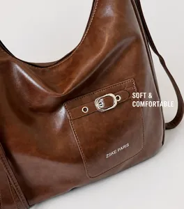 Detailed close-up of brown faux leather bag with silver metal buckle and ZSKE logo