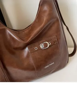 Detailed close-up of brown faux leather bag with silver metal buckle and ZSKE logo
